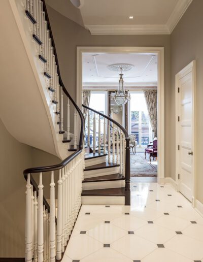 A hallway with a staircase and a chandelier.