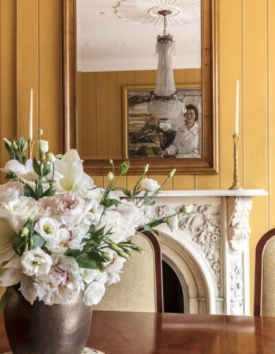 A vase of flowers on a table in front of a mirror.