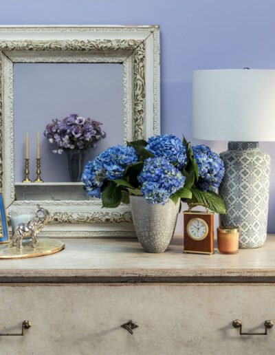 A white dresser with blue and white flowers and a mirror.