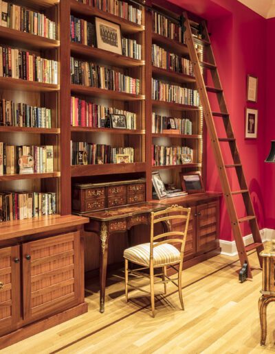 A living room with red walls and bookshelves.