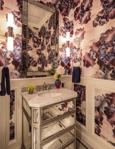 A bathroom with floral wallpaper and a mirror.