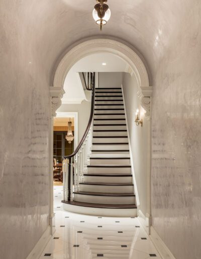 A hallway with a staircase and a chandelier.