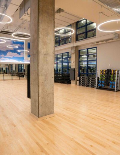 A gym with wooden floors and large windows.