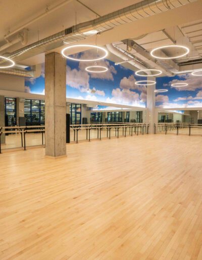 A gym with wooden floors and a ceiling with clouds.