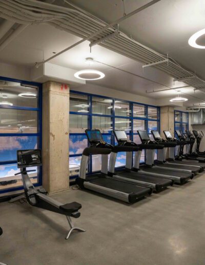 A gym with tread machines and large windows.