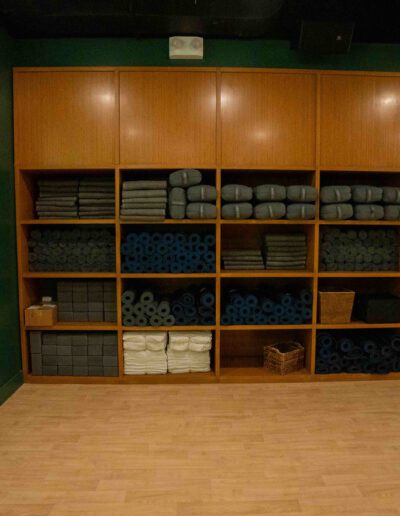 A room with a green wall and shelves full of yoga mats.