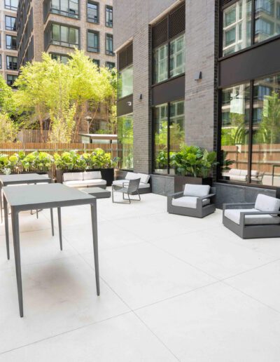 A white patio with furniture and plants in the middle of a building.