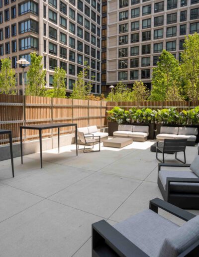 A patio with furniture and plants in the middle of a city.