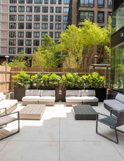 A patio with furniture and plants in the middle of a city.