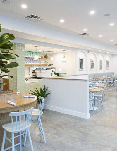 The interior of a restaurant with white tables and chairs.