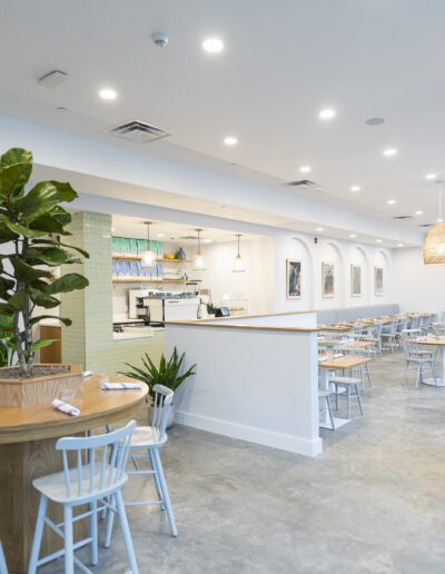 The interior of a restaurant with white tables and chairs.