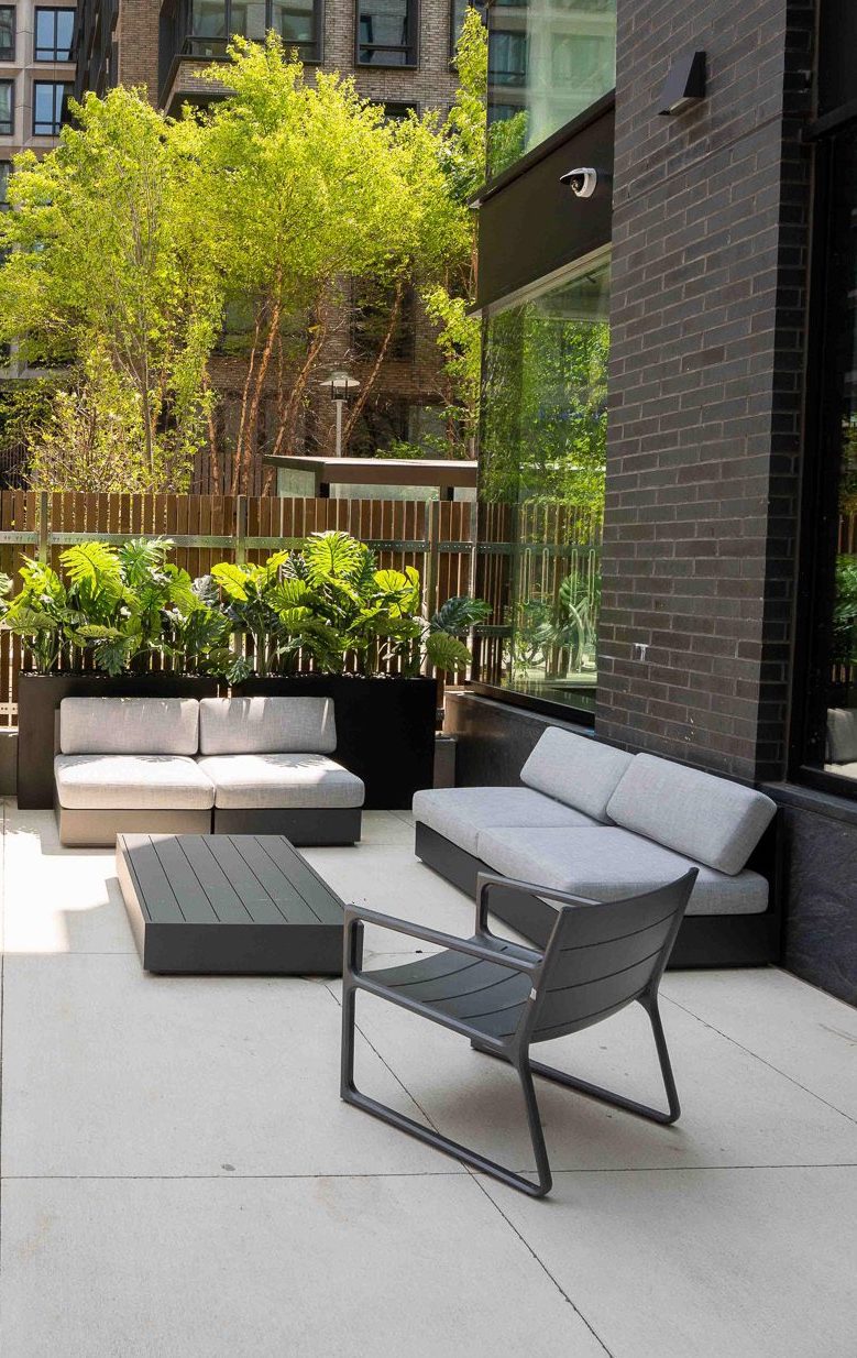 An outdoor patio with grey furniture and plants.